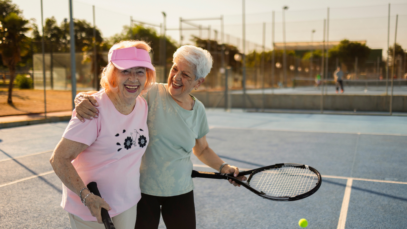 Two mature women play a game of tennis on a warm summer evening. They both have healed from fractures without medication using Fracture Healing's LIPUS technology.