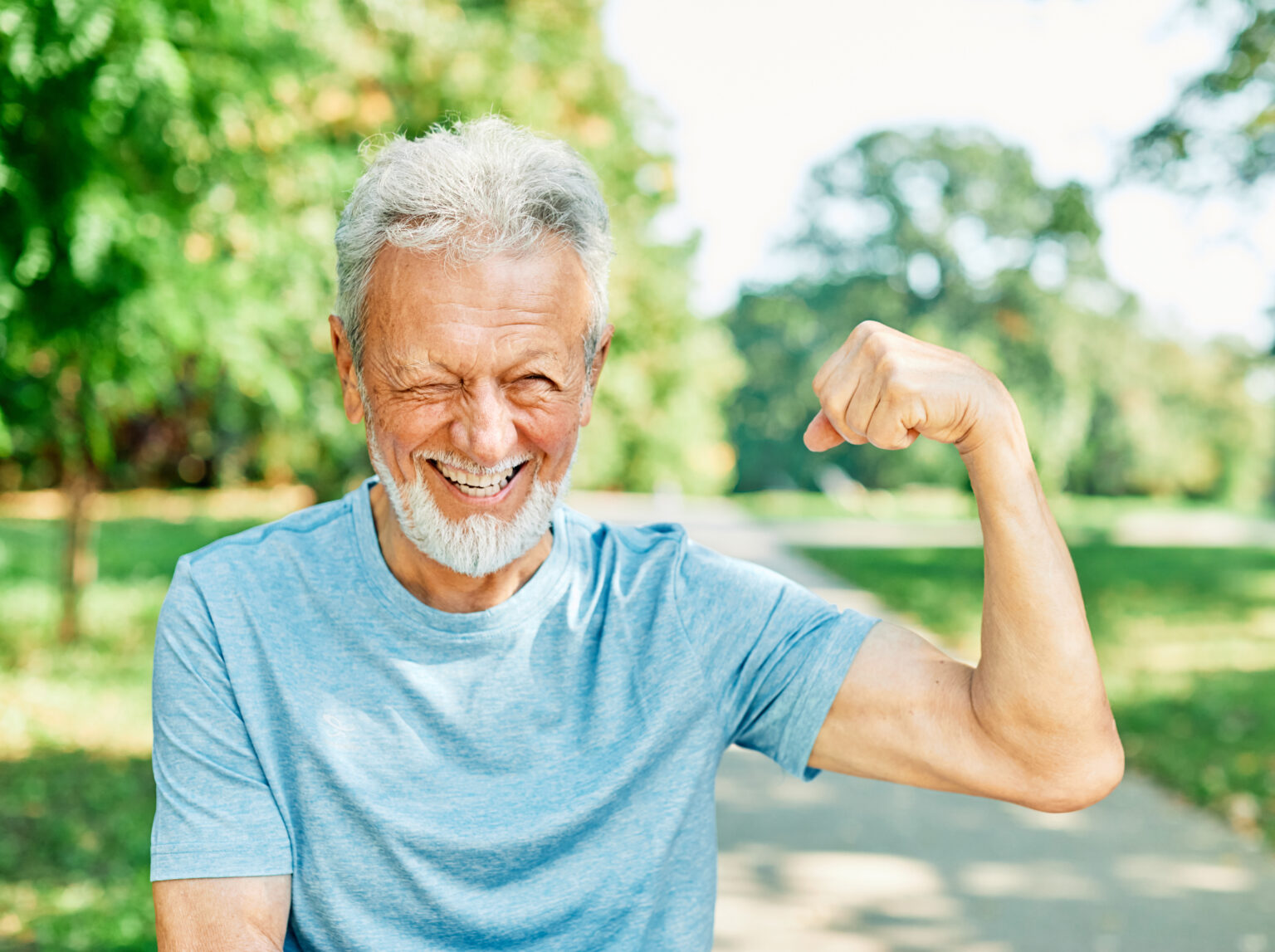 A mature man faces the camera and flexes his bicep—he's enjoying his physical fitness and bone density.