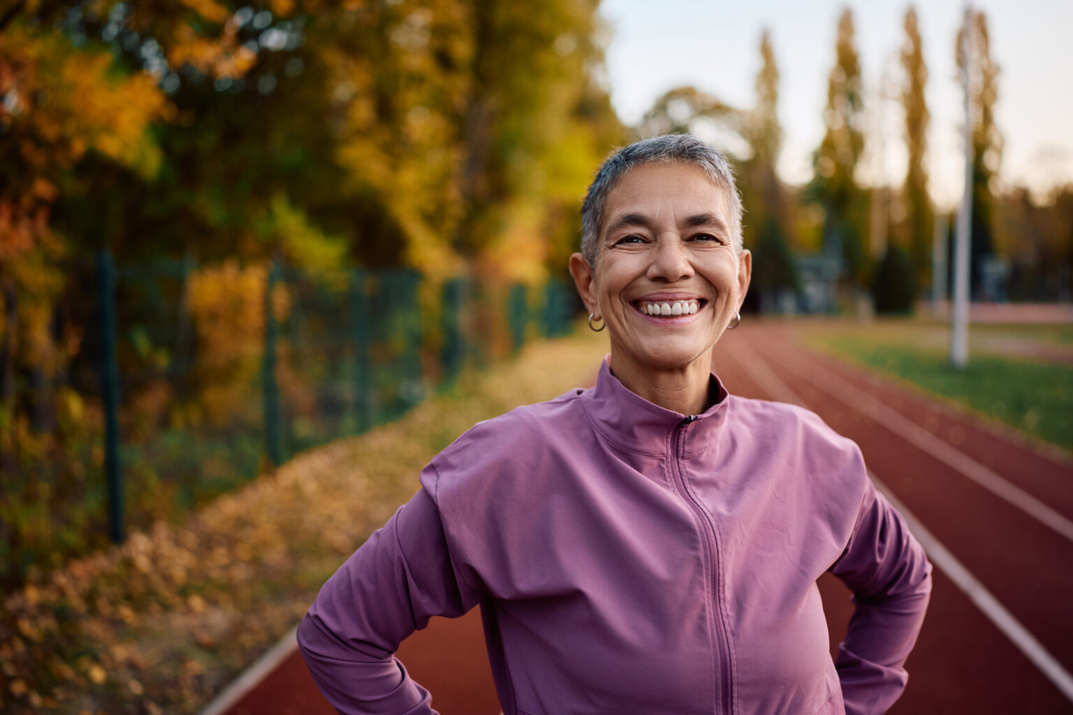 A healthy mature woman gets ready to run on a track; her bone density has been improved by her low-density vibration device.